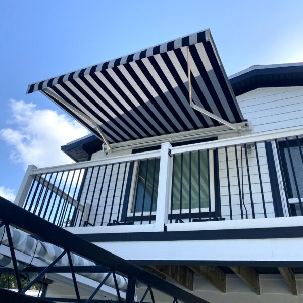 Custom black and white striped retractable awning installed on a residential balcony by Cover Up Awning in the Tampa Bay area