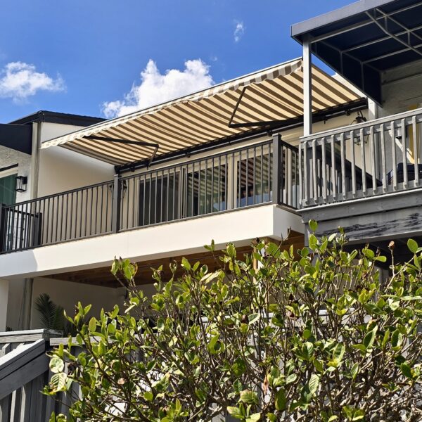 Custom tan and brown striped retractable awning installed on a second-story balcony in Tampa Bay, Florida by Cover Up Awning Company