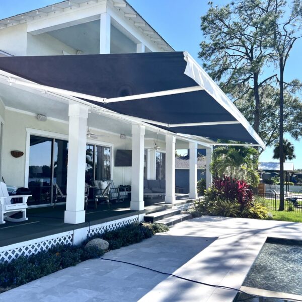 Custom charcoal retractable patio awning installed over a pool deck on a residential home in Tampa, Florida by Cover Up Awning Company
